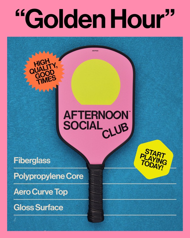 The Golden Hour paddle, pink with a yellow sun, on a blue court